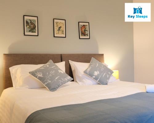 Una cama con sábanas blancas y almohadas en un dormitorio en Spacious Modern House At Keysleeps Short Lets Northampton With Free Parking Garden, 