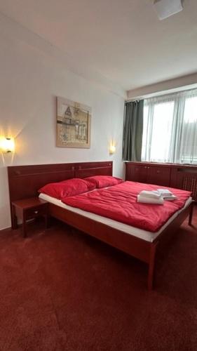 a bedroom with a bed with red sheets and a window at Hotel Bothe in Považská Bystrica