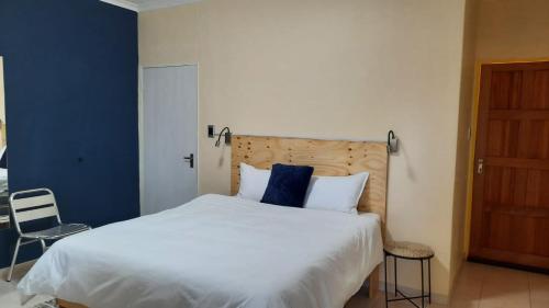 1 dormitorio con 1 cama blanca grande y pared azul en Steps Accommodation, en Gobabis