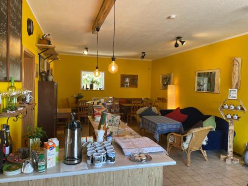 a living room with yellow walls and a table at Pension Grasse Hofladen Cafe GenießerImbiss Kehrigk in Kehrigk