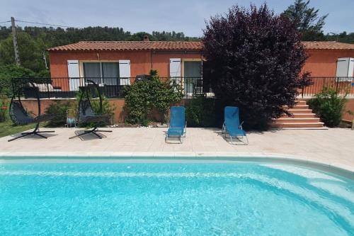 a swimming pool with two chairs and a house at Maison en Provence verte entre mer et lacs in Camps-la-Source