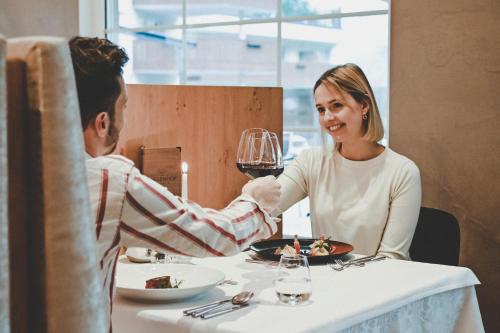 Un uomo e una donna seduti a un tavolo con un bicchiere di vino di Wiesenhof Gardenresort a San Leonardo in Passiria