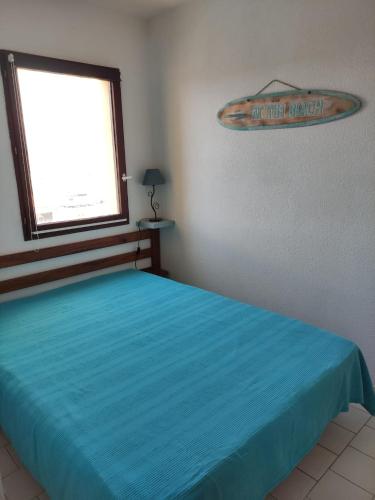 - une chambre avec un lit doté d'un couvre-lit bleu et d'une fenêtre dans l'établissement Cap d' Agde La conque, au Cap d'Agde