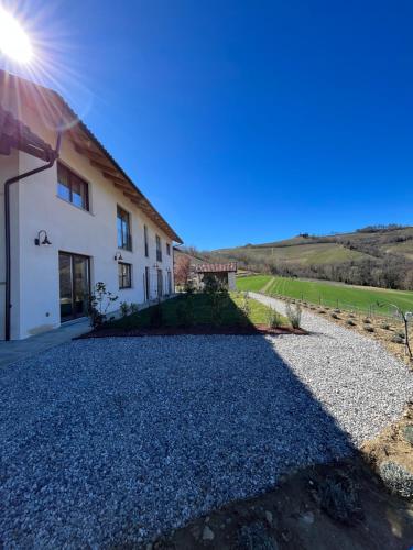 a house with a gravel driveway in front of it at Le Cornici - Cascina di Charme in Diano dʼAlba