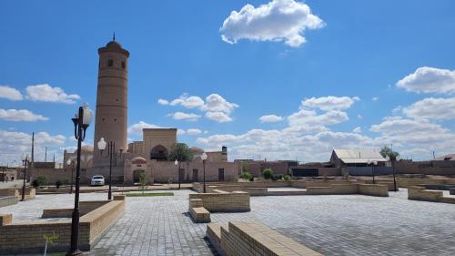 uma mesquita com uma torre de relógio numa cidade em madrasah Polvon-Qori boutique hotel em Khiva