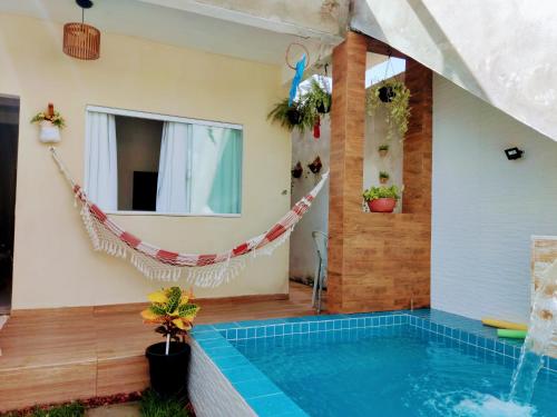 a swimming pool with a hammock next to a house at Casa Aconchegante com Piscina Barra do Jacuípe in Camaçari