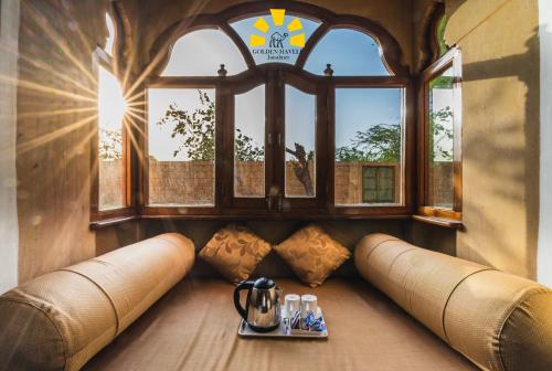 a room with a window and a couch with a tray of drinks at Hotel Golden Haveli in Jaisalmer
