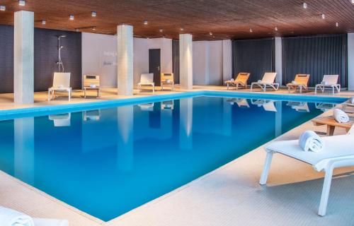 uma piscina num hotel com cadeiras e mesas em Victoria Hotel & Residence em Villars-sur-Ollon