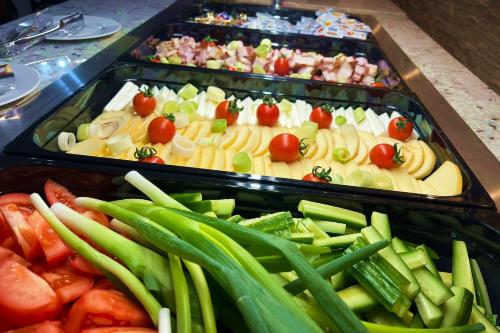 ein Buffet mit Speisen, darunter Gemüse auf Tabletts. in der Unterkunft Hotel Soimul in Poiana Brașov