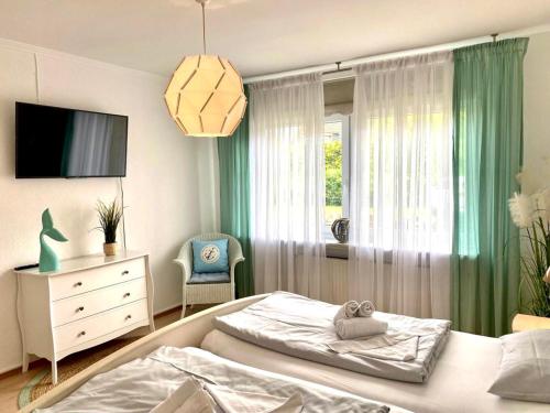 Schlafzimmer mit einem Bett, einem TV und einem Fenster in der Unterkunft MEI71 Ferienwohnung Strandlust F in Niendorf