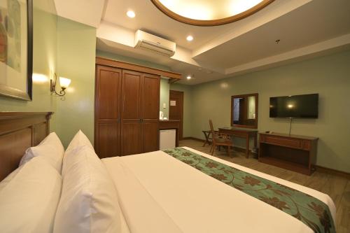 a hotel room with a bed and a television at Paragon Hotel and Suites in Baguio