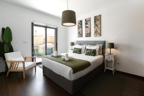 a bedroom with a large white bed and a chair at Baleal Deluxe Flat in Ferrel