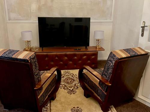 a living room with two chairs and a flat screen tv at Csaky Palace Bratislava in Bratislava