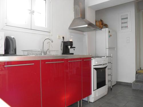 a kitchen with red cabinets and a white refrigerator at hantra thalasia 1 in Poros