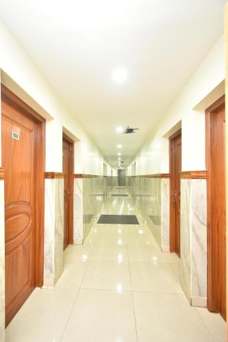 a long hallway with wooden doors and marble floors at HOTEL KANNUR CAPITAL CALTEX in Kannur