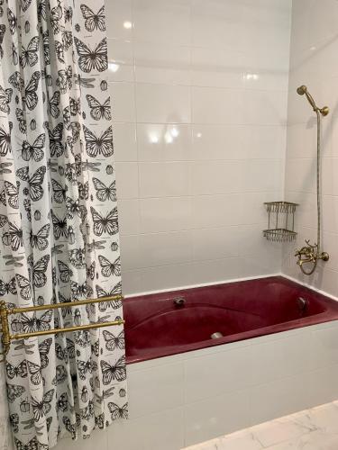 une salle de bain avec une baignoire rouge avec un rideau de douche dans l'établissement Maison de ville dans la Villa Brise des Pins, au Cannet