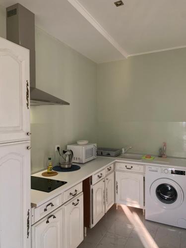 eine Küche mit weißen Schränken und einer Mikrowelle in der Unterkunft Maison de ville dans la Villa Brise des Pins in Le Cannet