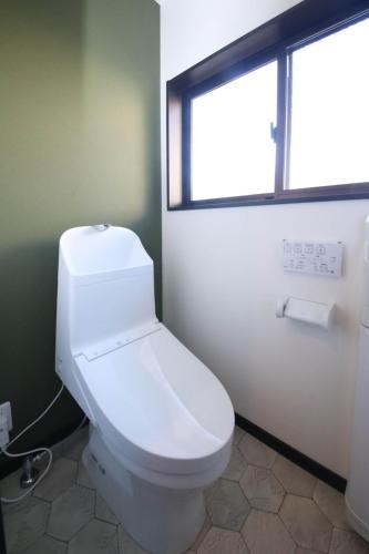 a white toilet in a bathroom with a window at さきみや in Goto