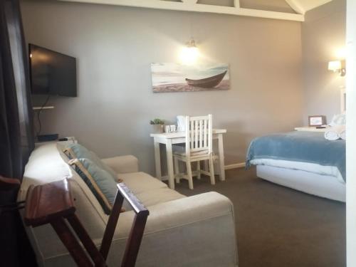 a bedroom with a bed and a couch and a table at Seaforth Guesthouse in East London