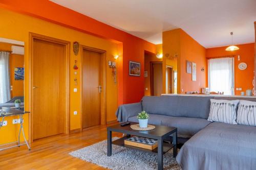 a living room with a blue couch and orange walls at Natural Oasis Villa in Nea Fokea