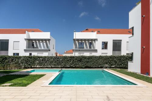 a swimming pool in front of two buildings at Baleal Deluxe Flat in Ferrel