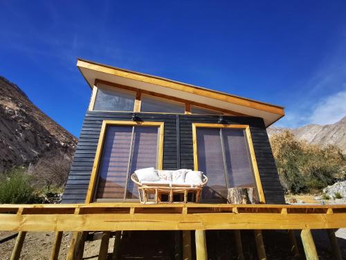 a tiny house on a deck with a chair on it at Cabaña Alma de Montaña, piscina privada in Monte Grande
