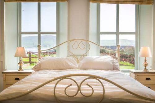 a bed with white sheets and pillows in a room with windows at Country Setting in the Middle of Dingle Town. in Dingle
