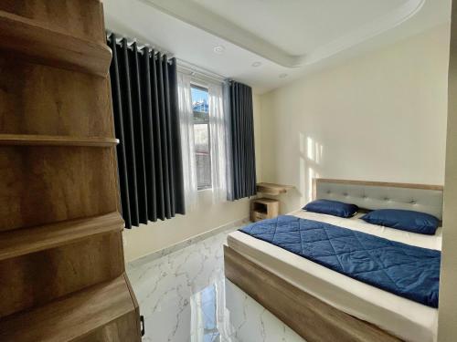 a bedroom with a bed with blue pillows and a window at Sweet Home LGBTQ in Ho Chi Minh City