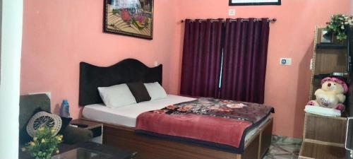 um quarto com uma cama e uma parede vermelha em Peaceful Home Stay em Khajurāho