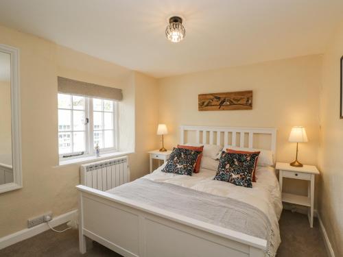 a bedroom with a white bed with two lamps and two windows at Wharf Cottage in Lechlade