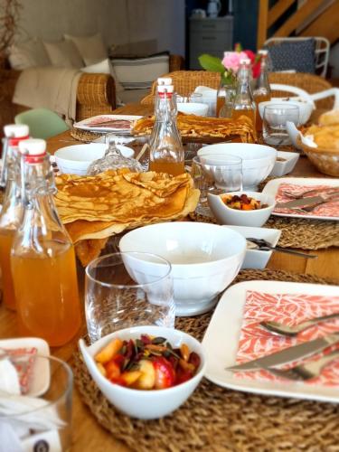 Una mesa cubierta con cuencos de comida y bebidas. en Ty Coz Breizh Chambres d'hôtes, en Guidel