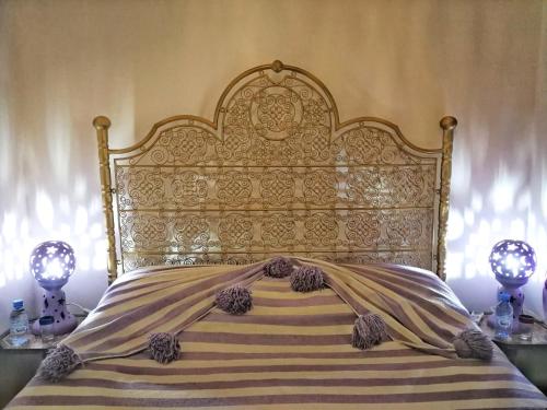 a bed with an ornate headboard and a blanket at Riad DAR BARBI in Marrakesh