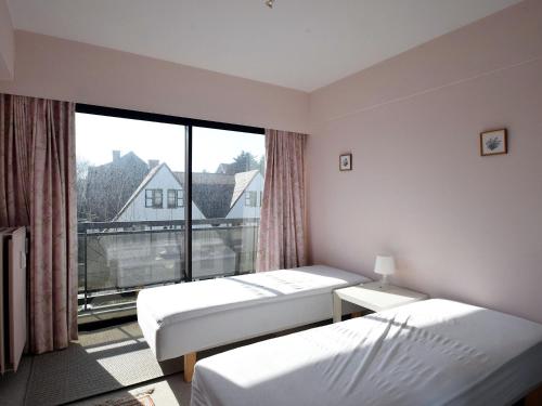een kamer met 2 bedden en een groot raam bij Bries 0202 apartment with a sunny terrace in De Haan