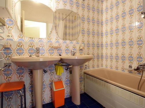 een badkamer met 2 wastafels, een bad en een spiegel bij Bries 0202 apartment with a sunny terrace in De Haan