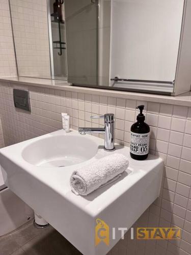a bathroom sink with a towel and a bottle of soap at Resort-Style Midnight, Braddon 1bd - Top Location in Canberra