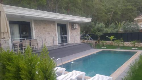 een zwembad met stoelen en een huis bij Antalya Silyan Villas in Gedeller