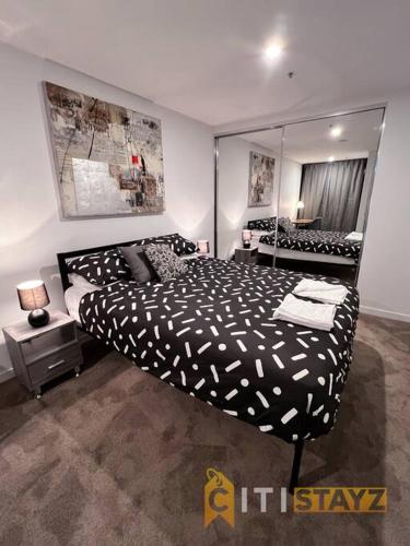 a bedroom with a black and white bed and a mirror at Resort-Style Midnight, Braddon 1bd - Top Location in Canberra