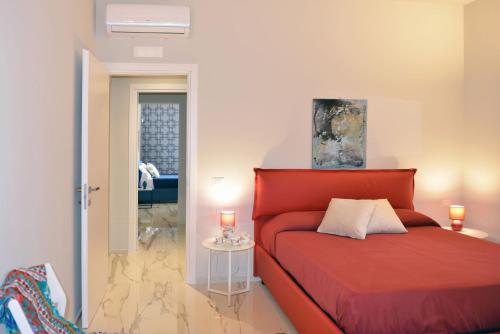 Un dormitorio con una cama roja y una mesa con velas en Villa Pica by PosarelliVillas, en San Corrado di Fuori