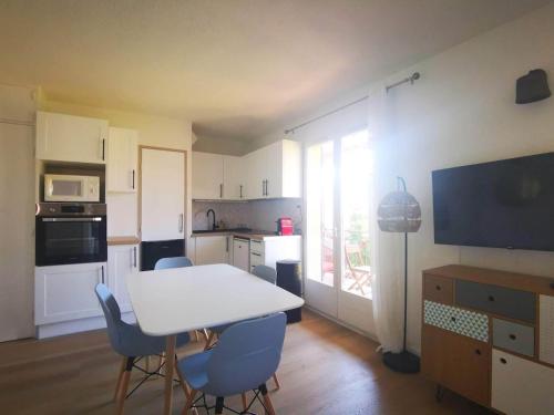 - une cuisine avec une table et des chaises blanches dans la chambre dans l'établissement Le Cocon vert T2 St Aygulf à 30m de la mer, à Saint-Aygulf