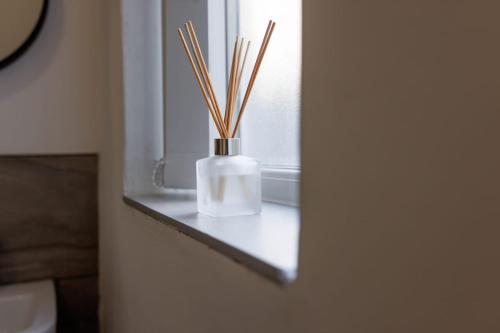 a vase with sticks in it sitting on a window sill at Newly Renovated Apartments in Liverpool - Extended Stay in Liverpool