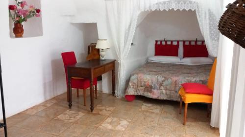 a bedroom with a bed and a desk and a bed with red chairs at Trullo Antelmi in Ceglie Messapica