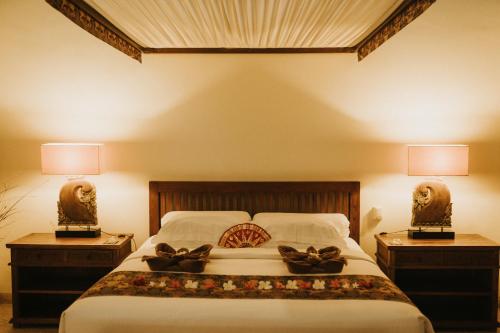 a bedroom with a bed with two night stands at ALOKA BAHARI Villas in Tejakula