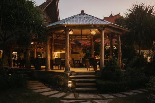 a wooden gazebo with a table and chairs at ALOKA BAHARI Villas in Tejakula