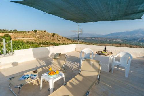 un patio con sedie e tavoli bianchi e ombrellone di Bella-Maria at Aptera with mountain and sea view - Ground Floor a Chania
