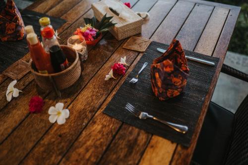 a wooden picnic table with a bottle of wine and flowers at ALOKA BAHARI Villas in Tejakula