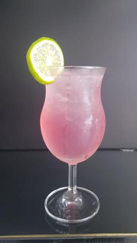 a glass with a pink drink with a lime on it at Riverfront Apartments Vientiane in Vientiane