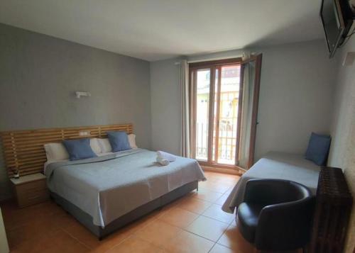 a bedroom with two beds and a chair and a window at Hotel Acebo Plaza Mayor in Jaca