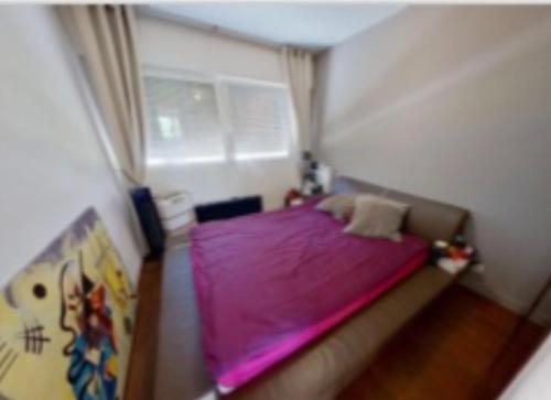 a small bedroom with a purple bed and a window at Chambres à loyers dans un Penthause in Bourg-la-Reine
