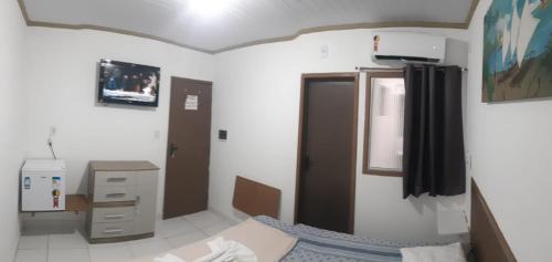 a room with a bed and a refrigerator at Pousada 4 estações in Suape