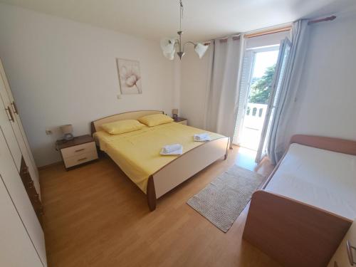 um quarto com uma cama amarela e uma janela em Apartmani Dijana em Rab